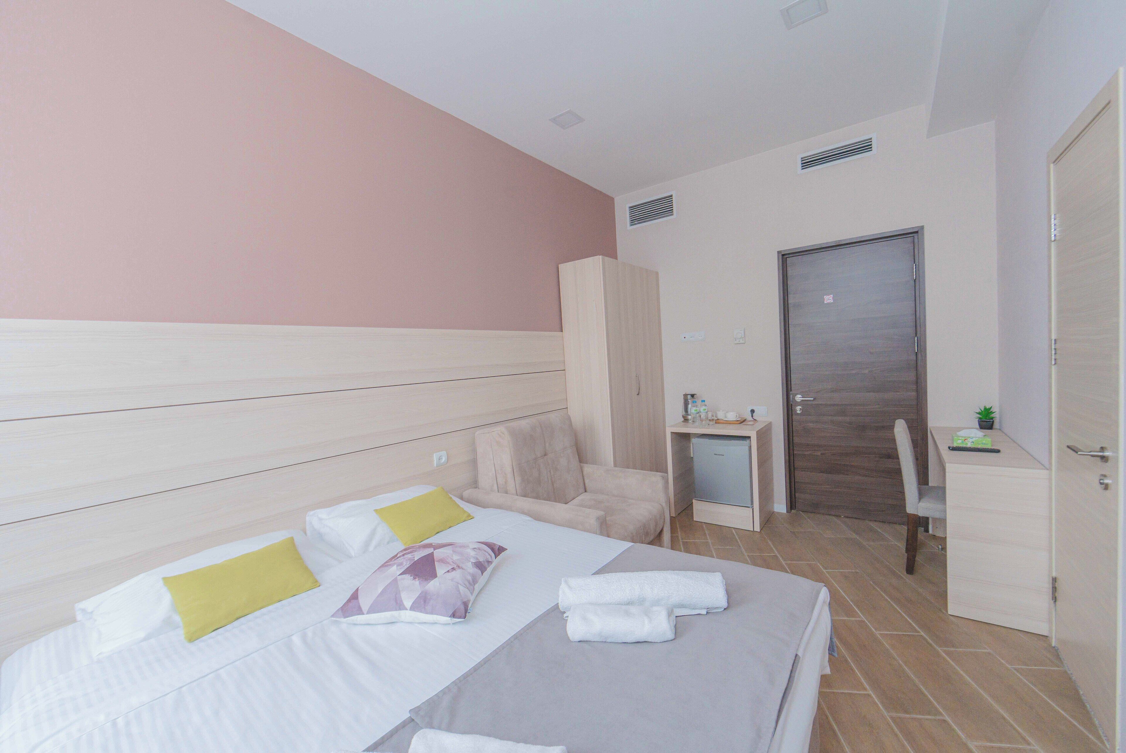 A hotel room with a bed, a desk, a wardrobe, and a door.