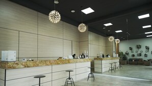 Een moderne receptie met een marmeren balie, barstoelen en hanglampen.