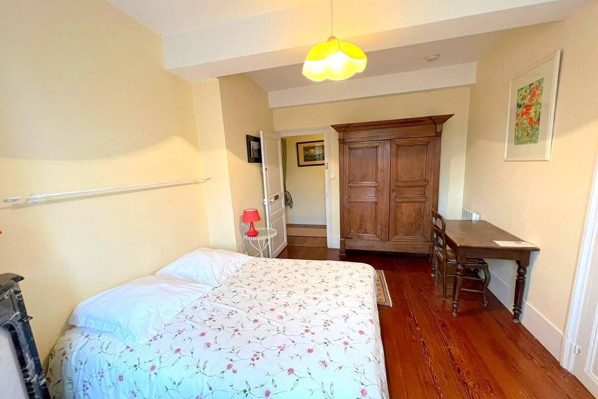 A bedroom with a bed, a wooden desk, and a wardrobe.