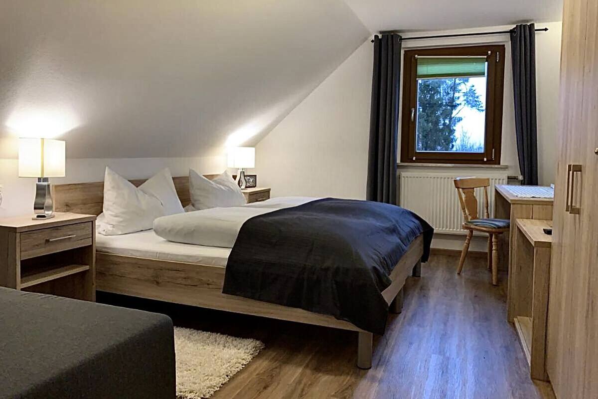 A bedroom with a bed, bedside tables, a desk, and a chair.