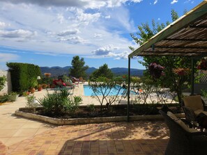 Un espace piscine offrant une vue sur les montagnes, agrémenté de plantes en pot et de mobilier d’extérieur.