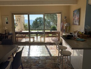 A spacious kitchen with a large dining area, a sliding glass door leading to an outdoor patio, and a view of the surrounding landscape.
