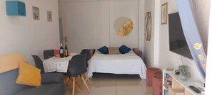 Une pièce de taille modeste comprenant un lit, un canapé, une table à manger et un téléviseur.