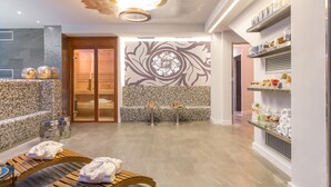Moderni spa-huone, jossa on puinen penkki, lasipöytä ja seinä, jossa on koristeellinen kuvio.
