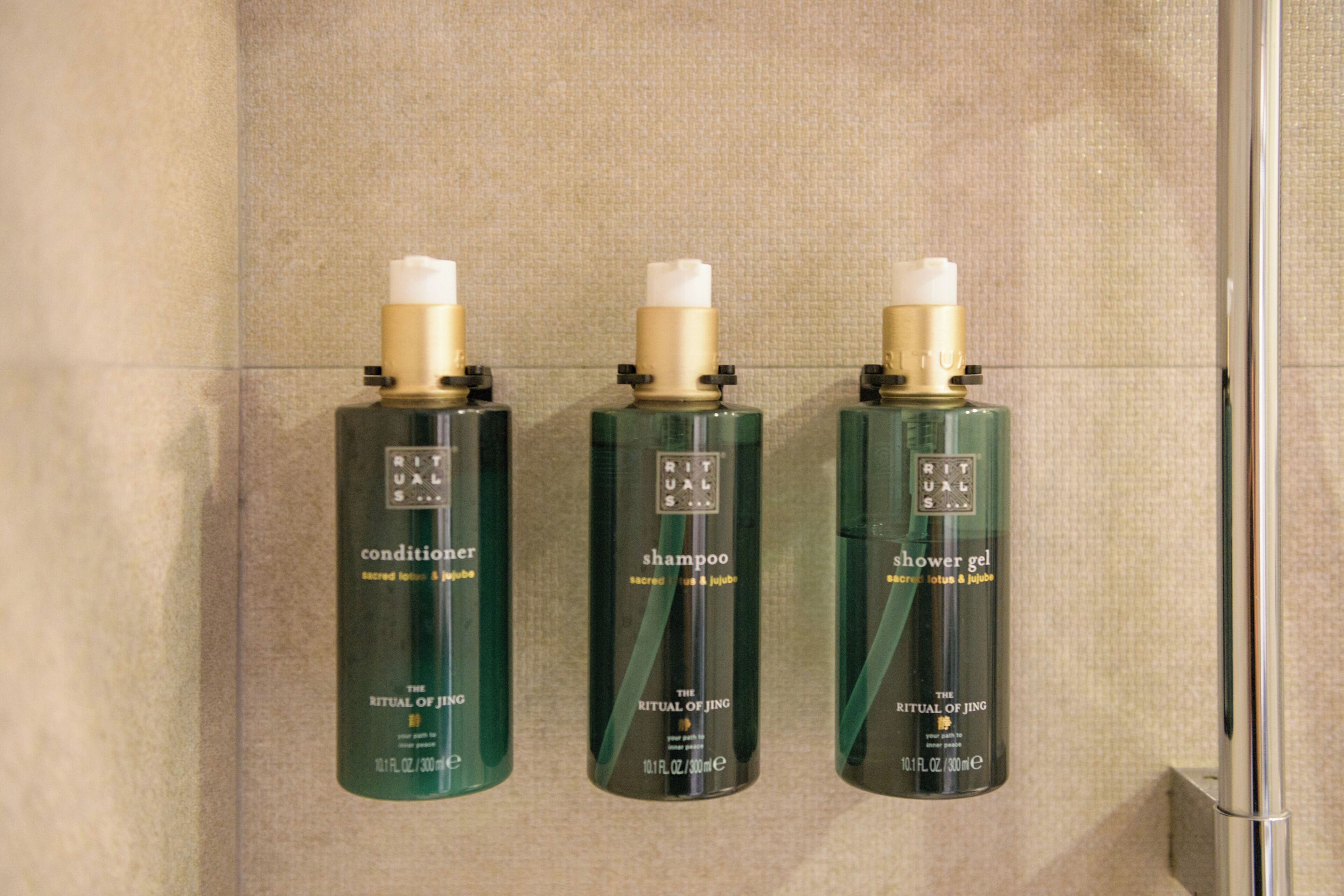 Three bottles of Ritual of Jing products on a wall.