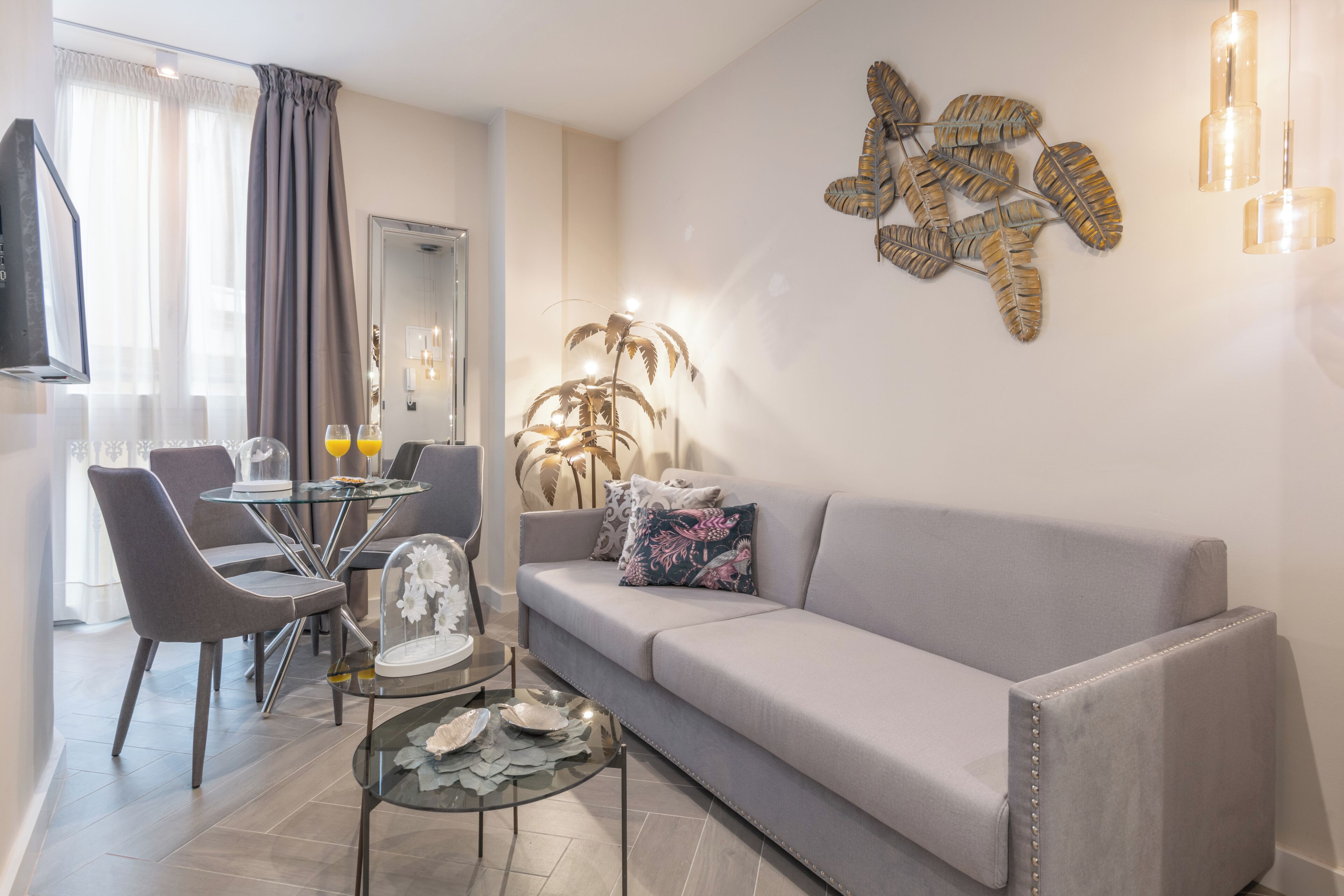 A modern living room with a sofa, dining table, chairs, and a decorative wall piece.