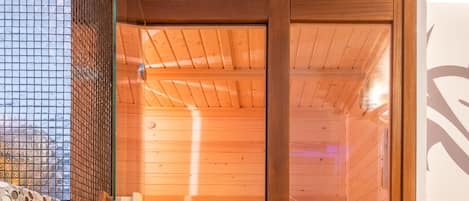 A sauna with wooden walls and a glass door, a bench, and a small shelf.