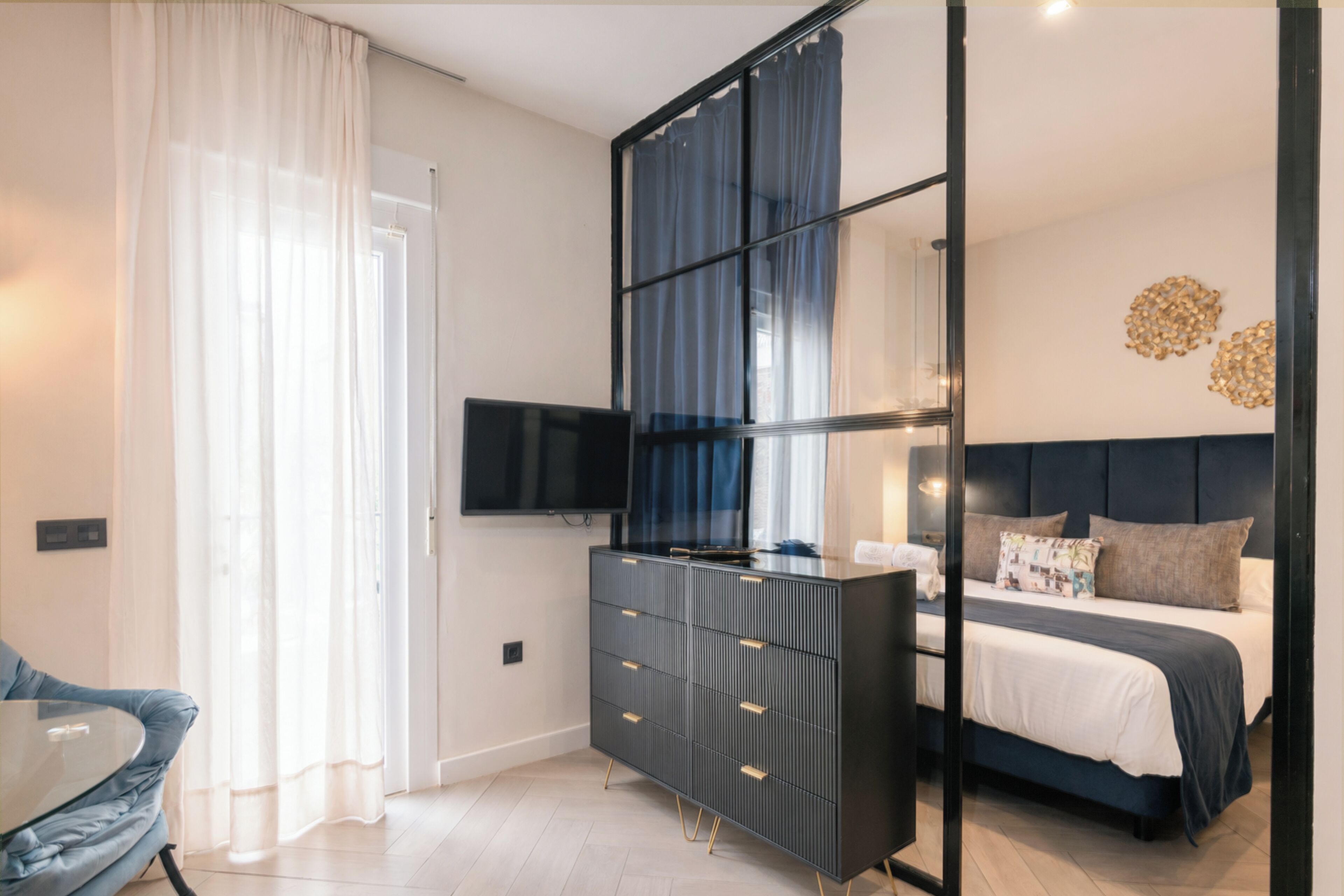 A modern bedroom with a bed, a dresser, a TV, and a chair.