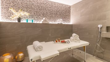 A modern spa room with a massage table, towels, and decorative items.