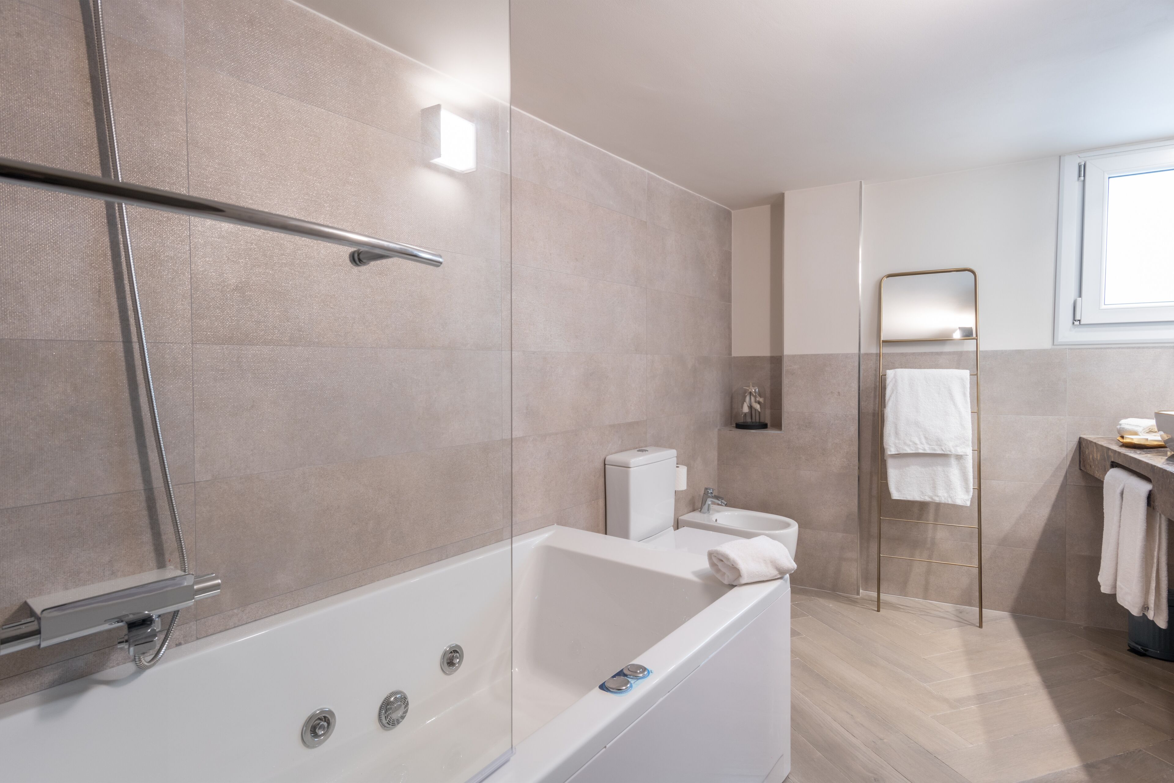 A modern bathroom with a glass-enclosed shower, a freestanding bathtub, a toilet, and a mirror with a towel rack.