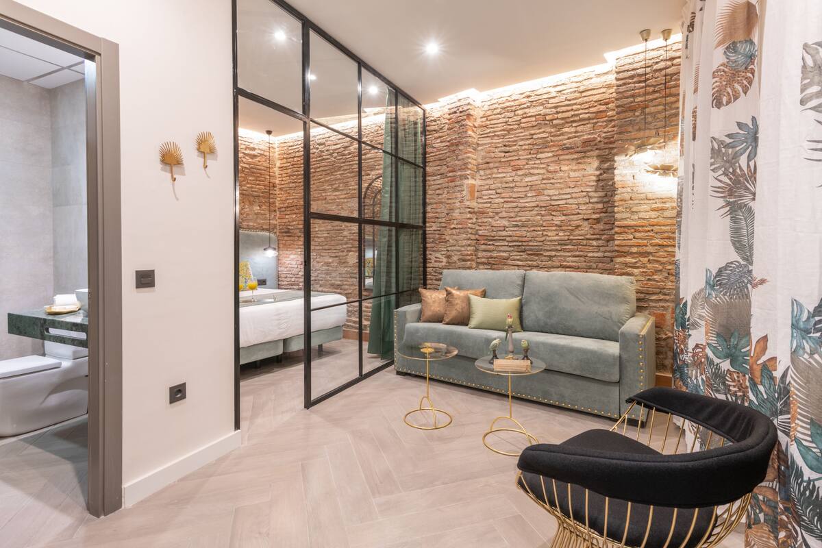 A modern living room with a grey sofa, a black chair, and a glass partition.