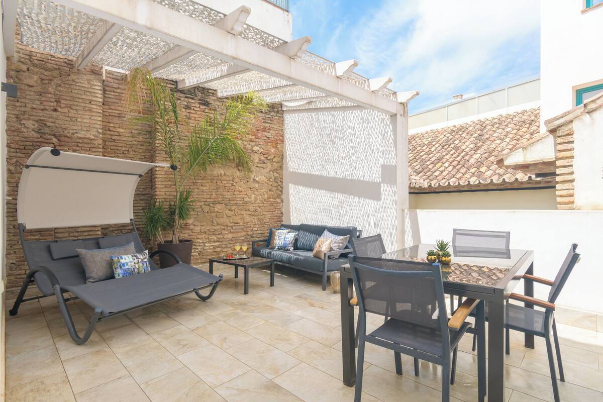 A patio with a sofa, chairs, a table, and a laptop.