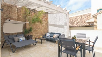 Un patio con sofá, sillas, una mesa y una computadora portátil.