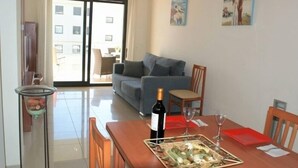 A dining area with a wooden table, chairs, a bottle of wine, and a tray of food.