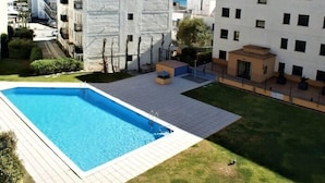 A residential building with a swimming pool, a small patio area, and a view of the sea.