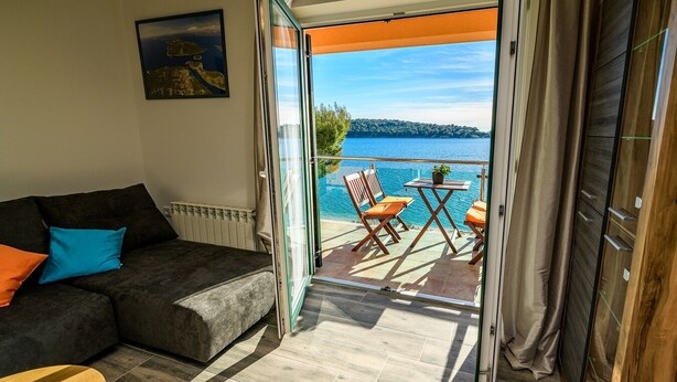 A balcony with a view of a lake and a table with chairs. - Apartment in Mali Lošinj with Seaview, Balcony, Air condition, WIFI (4896-1) (Mali Lošinj)
