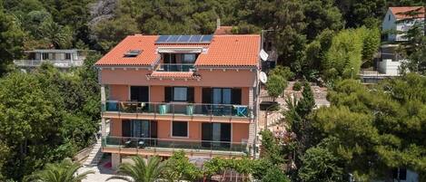 Un immeuble à plusieurs étages, doté d’un toit recouvert de tuiles rouges, de balcons et de panneaux solaires.
