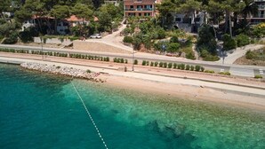 A coastal hotel with a clear view of the sea, a paved walkway, and lush greenery.