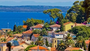 A coastal town with Mediterranean-style buildings, a clear blue sea, and lush greenery.