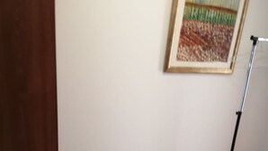 Ein Zimmer mit Holzboden, einem gerahmten Gemälde an der Wand und einem schwarzen Metallständer.
