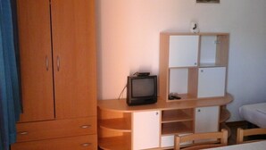 A bedroom with a wooden wardrobe, a bed, a TV on a wooden desk, and a painting on the wall. - Apartment in Metajna with Seaview, Balcony, Air condition, WIFI (4890-2) (Metajna)