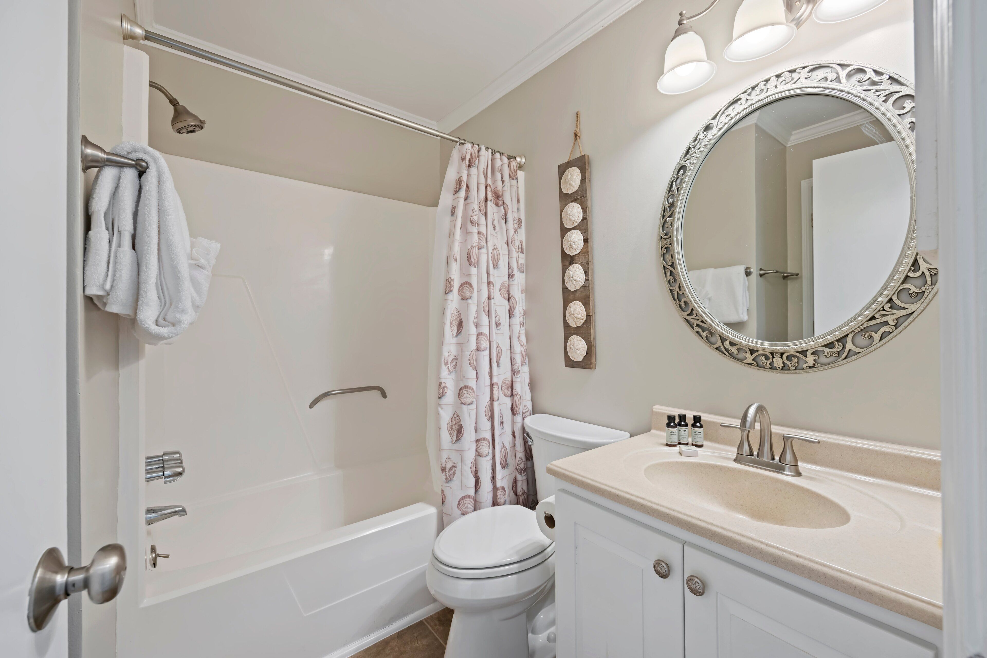 A bathroom with a bathtub, toilet, vanity with a sink, and a large mirror.