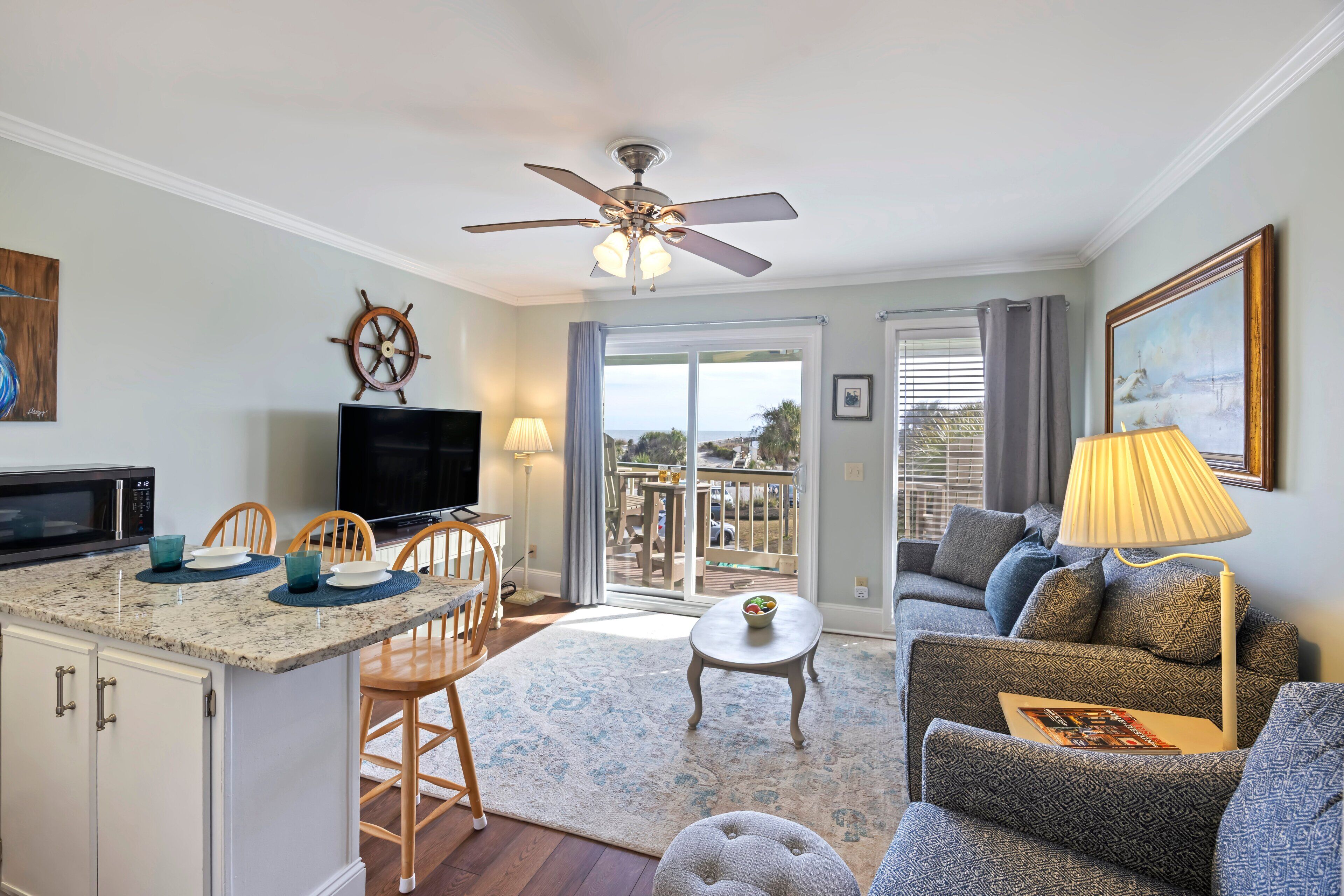 A modern living room with a television, dining area, and a balcony with a view.