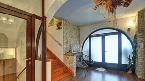Una escalera conduce a una habitación con pared de piedra, puerta de cristal y vistas al exterior.