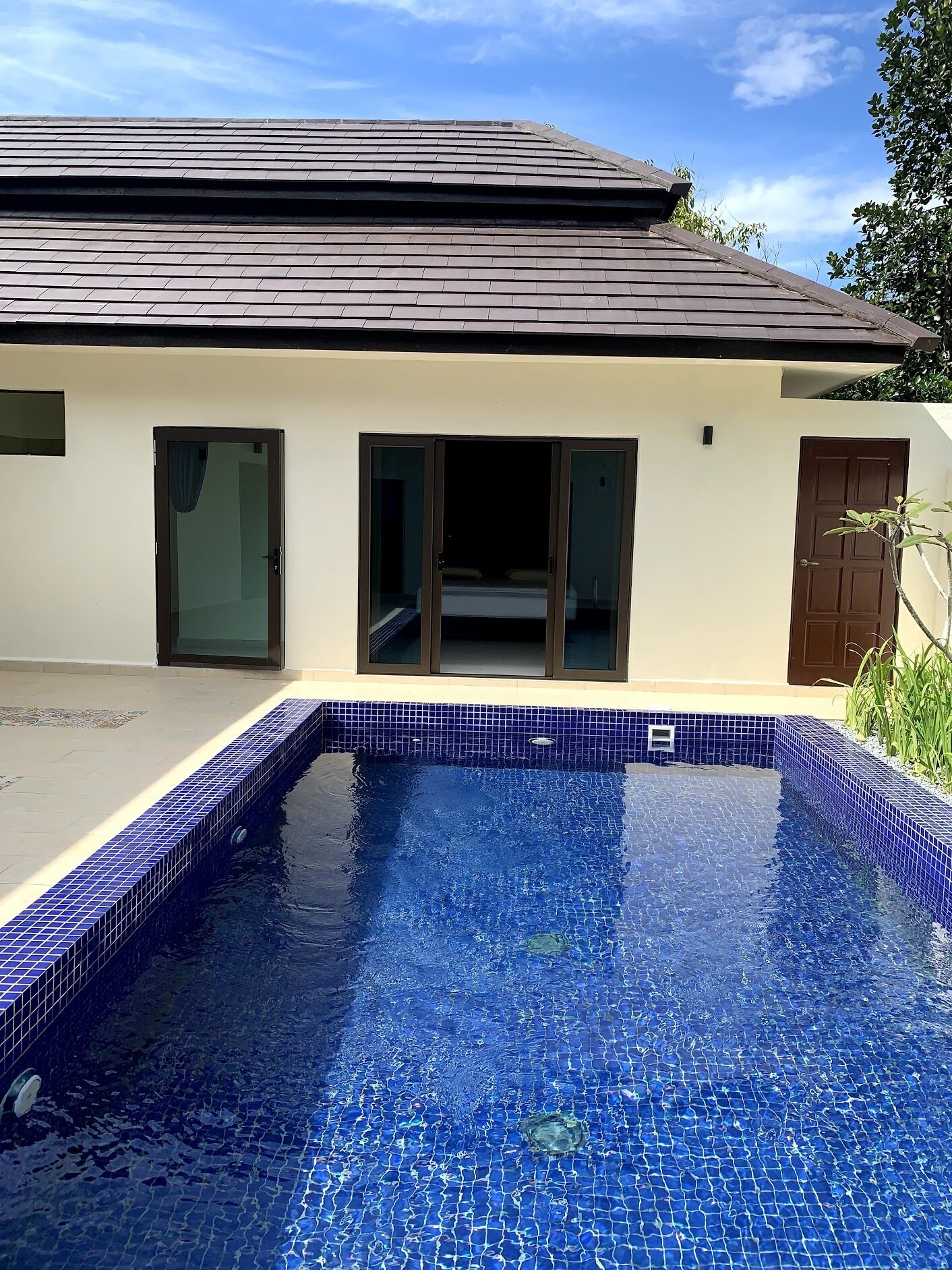 A house with a swimming pool, a tiled roof, and a door.