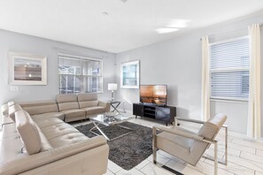 Relax in this stylish living room with a sectional sofa, flat-screen TV, and glass coffee table.