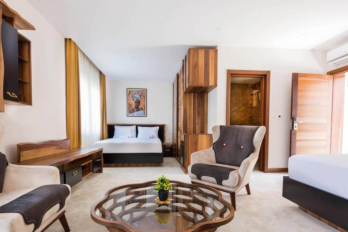 A modern hotel room with a bed, a sofa, a coffee table, and a wardrobe.