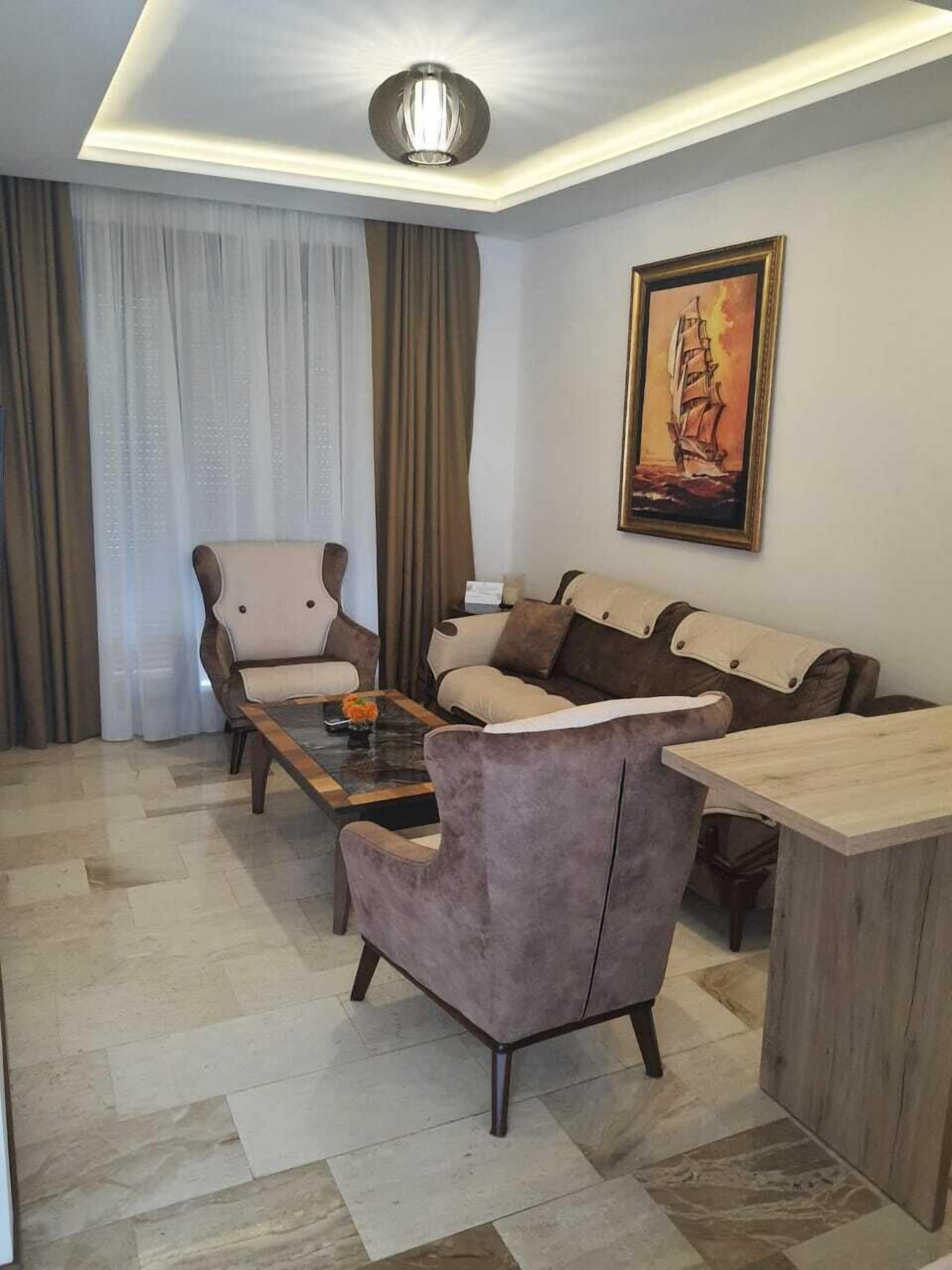 A living room with a sofa, armchairs, a coffee table, and a painting on the wall.