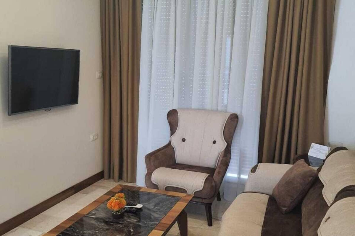 A living room with a flat-screen TV, a sofa, a chair, and a coffee table.