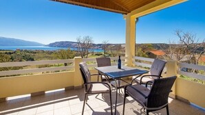 A covered outdoor seating area with a table and chairs, overlooking a scenic landscape with mountains and a body of water. - Apartment in Lopar with Terrace, Air condition, WIFI (4918-1) (Lopar)