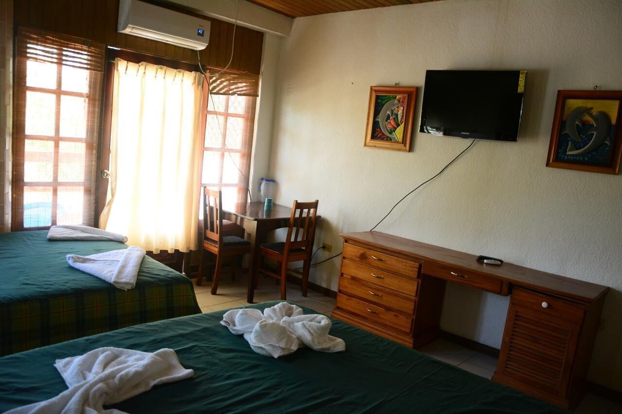 A hotel room with two beds, a desk, a chair, and a television on the wall.
