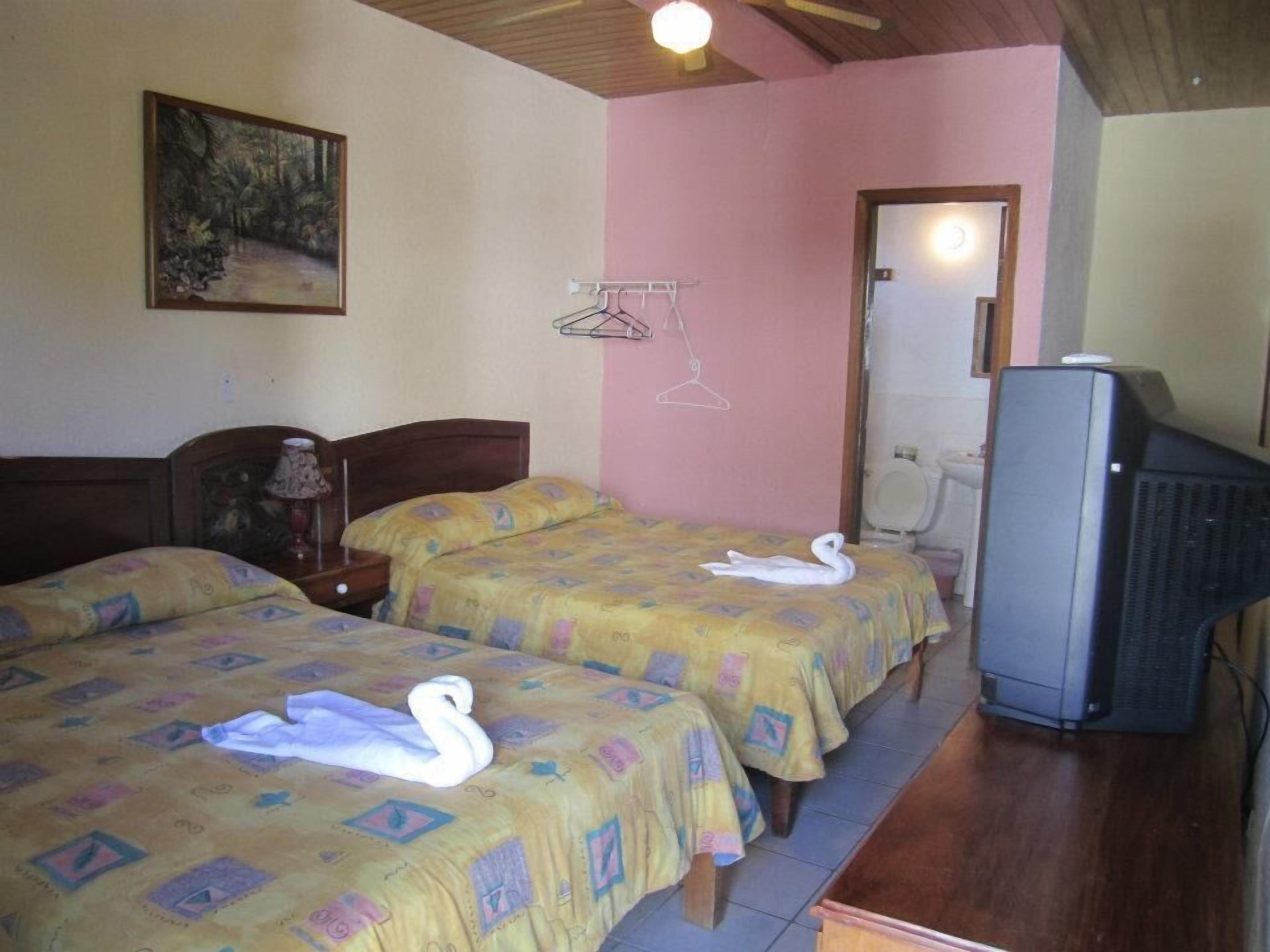 Ein Hotelzimmer mit zwei Betten, einem Fernseher und einem Bild an der Wand.
