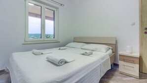 A single-bed room with a wooden headboard, a window with a view, a bedside table with a tissue box, and a door with a lock. - Apartment in Pirovac with Seaview, Terrace, Air condition, WIFI (4925-2) (Pirovac)