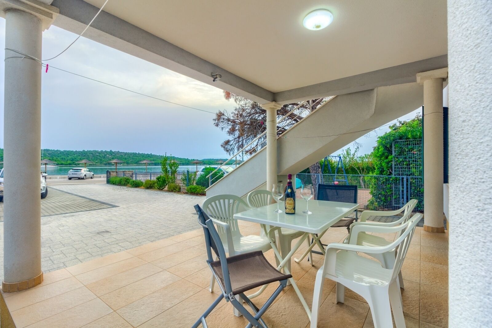 Eine überdachte Terrasse im Freien mit Tisch und Stühlen, mit Blick auf eine malerische Wasserlandschaft und eine Brücke.