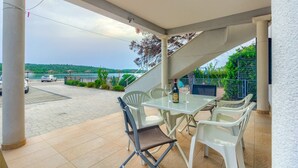 A covered outdoor patio with a table and chairs, overlooking a scenic view of a body of water and a bridge. - Apartment in Pirovac with Seaview, Terrace, Air condition, WIFI (4925-2) (Pirovac)