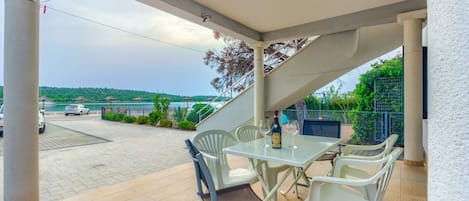 A covered outdoor patio with a table and chairs, overlooking a scenic view of a body of water and a bridge.