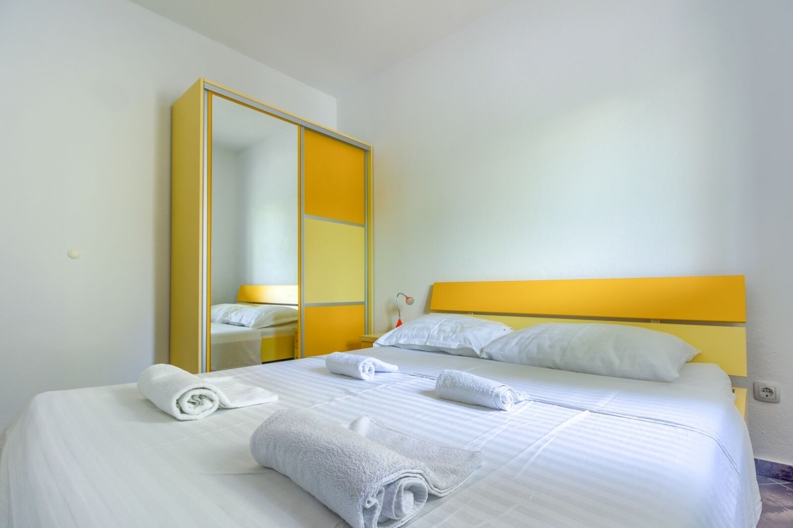 Quarto de hotel com uma cama, duas mesas de cabeceira, um espelho e um guarda-roupa.