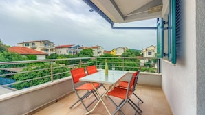 A balcony with a table and chairs, overlooking a residential area with houses and greenery.