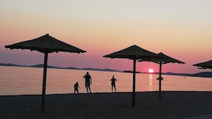 A beach scene with umbrellas and people at sunset.