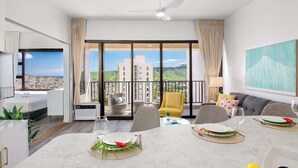 A modern hotel room with a dining area, a balcony with a view, and a large window. - Ocean-view condo w/ pool near Waikiki Beach (Honolulu)