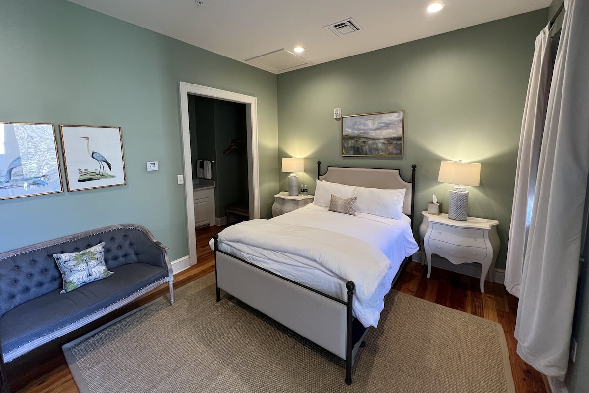 Une chambre à coucher comprenant un lit, des tables de chevet, une commode, un canapé et des œuvres d’art accrochées aux murs.