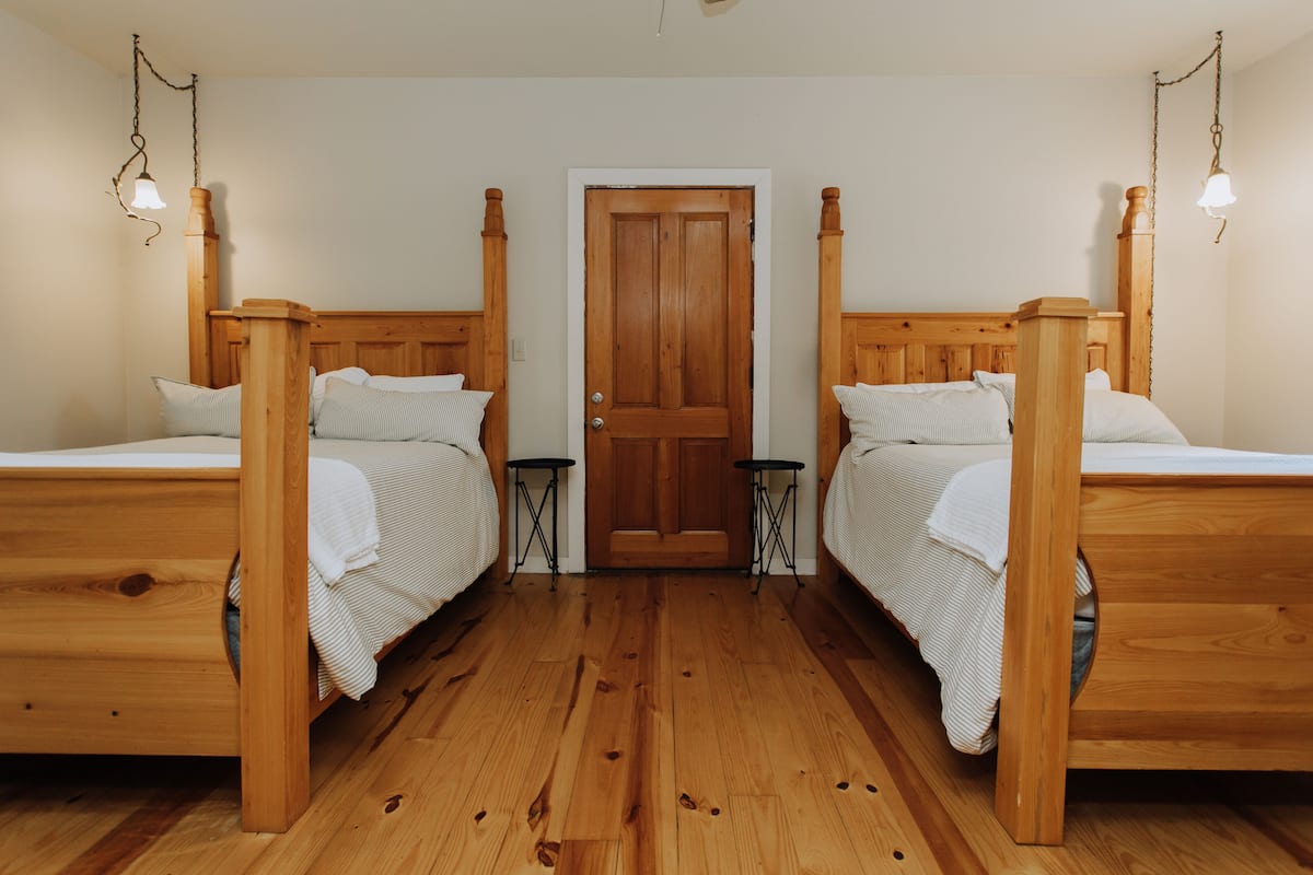 Une pièce avec deux lits en bois, une porte en bois et un plancher en bois.