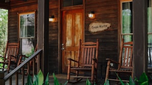 A wooden cabin with a porch, rocking chairs, and a sign reading "Crepe Myrtle".