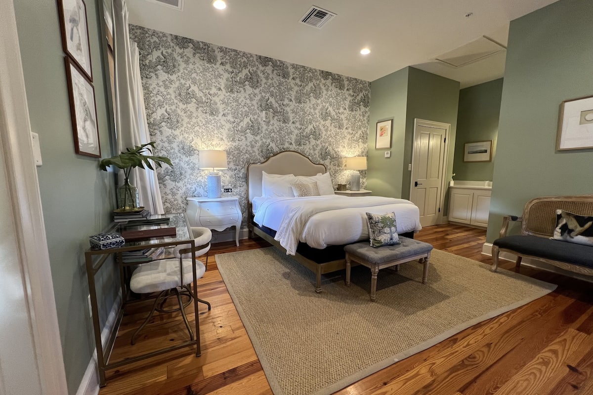 Une chambre à coucher avec un grand lit, des tables de chevet, un bureau et une chaise.