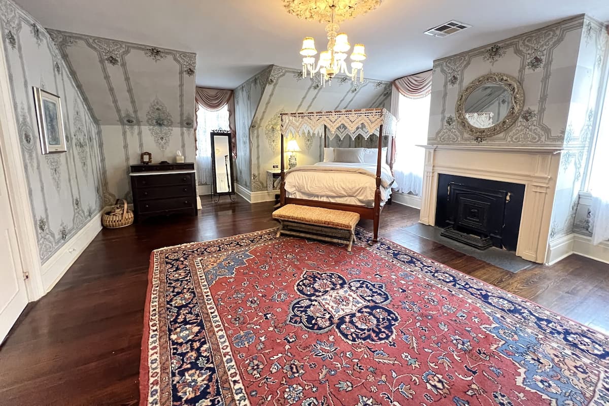 Une chambre à coucher avec un lit à baldaquin, un lustre, une cheminée et des décorations murales élaborées.