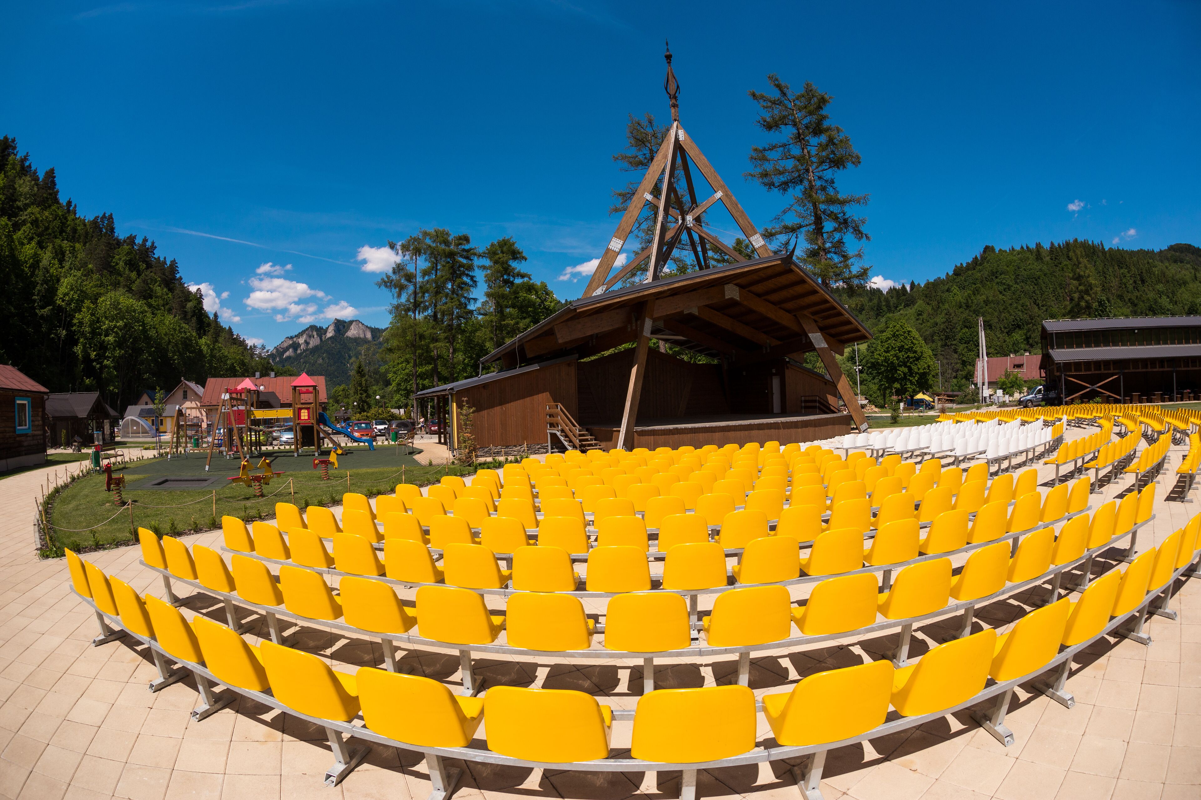 An outdoor amphitheater with yellow seats and a wooden stage structure.